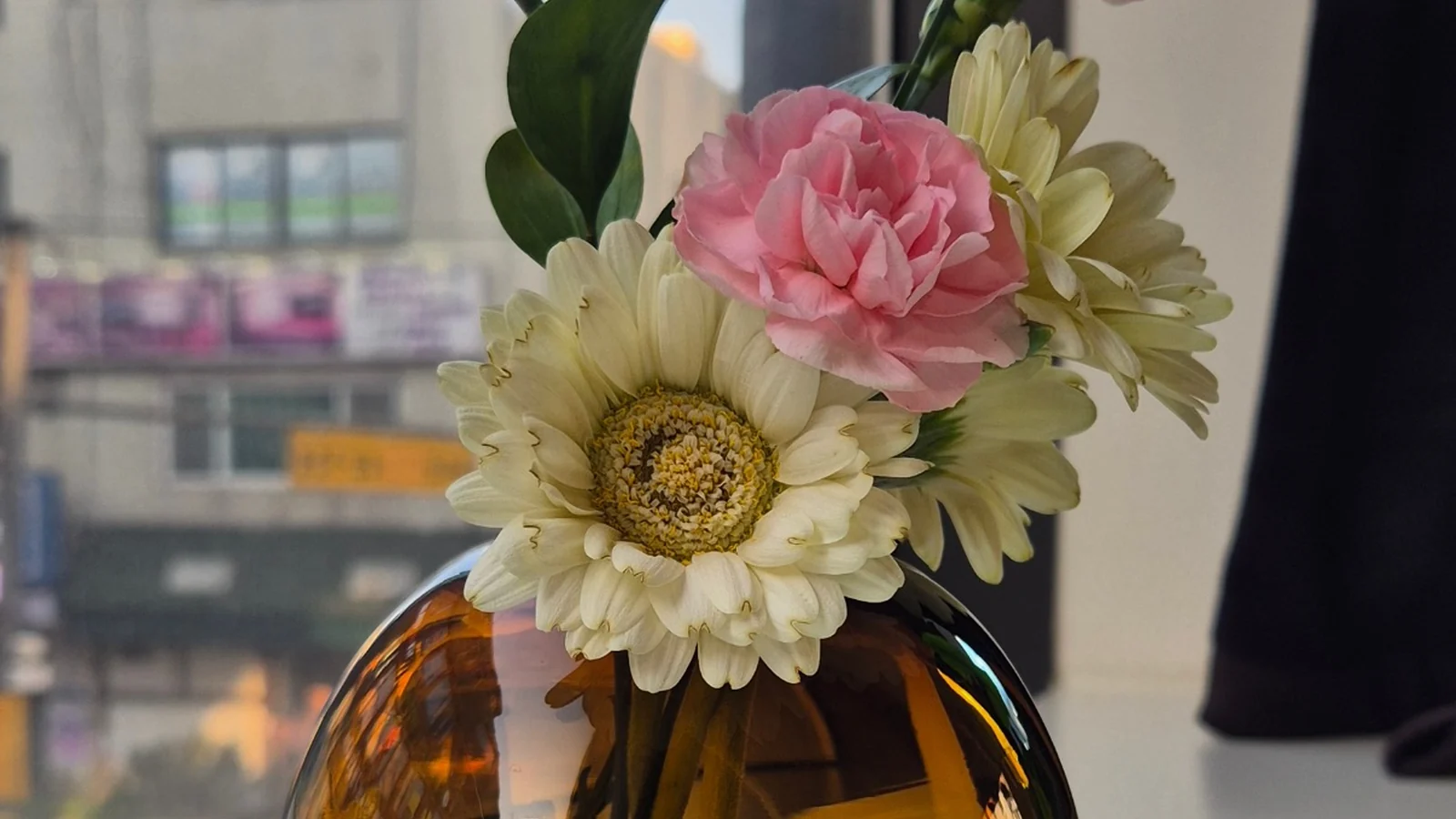 Pink and white flowers in a round amber vase