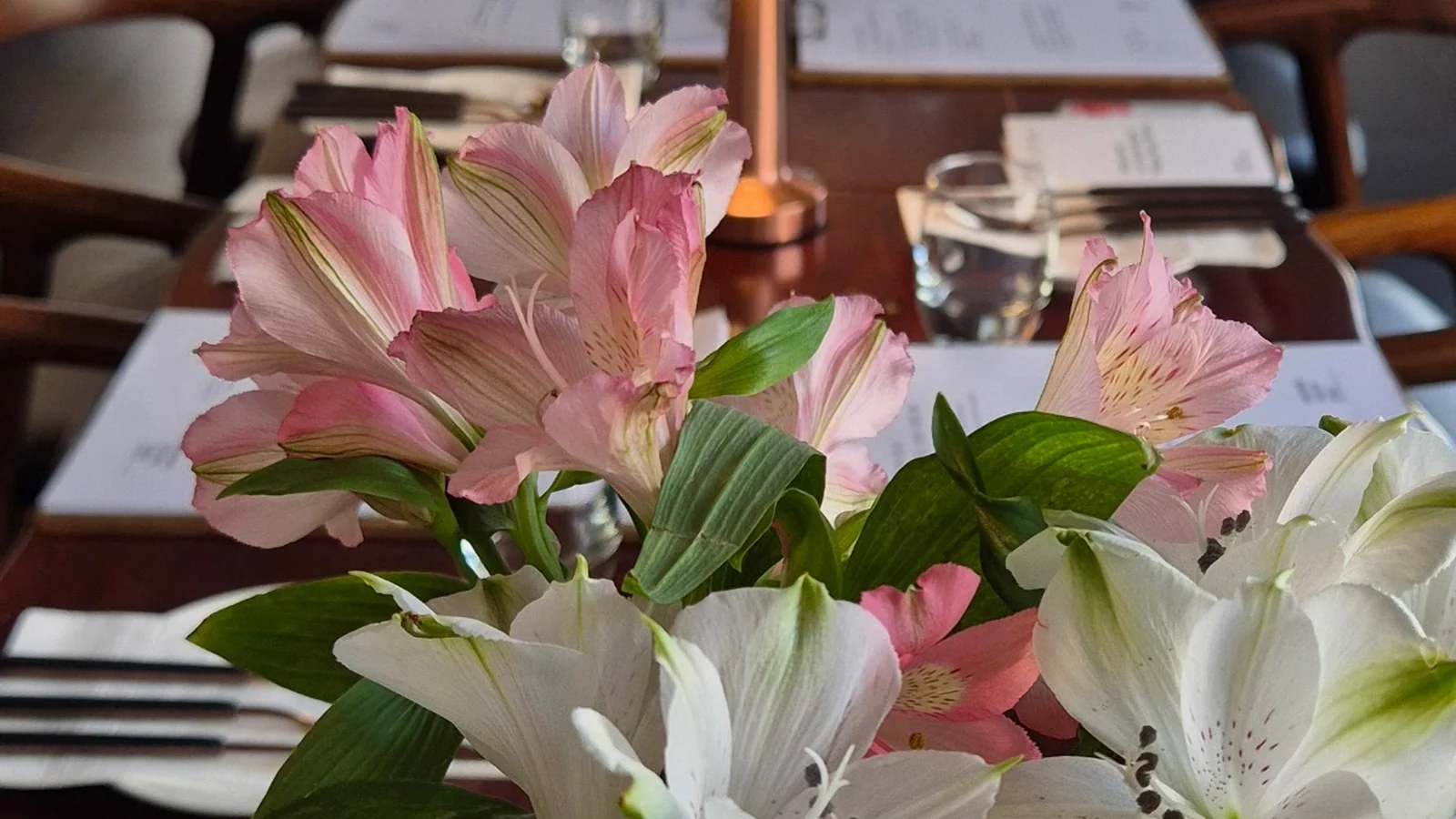 Pink and white fresh flowers beside a long table