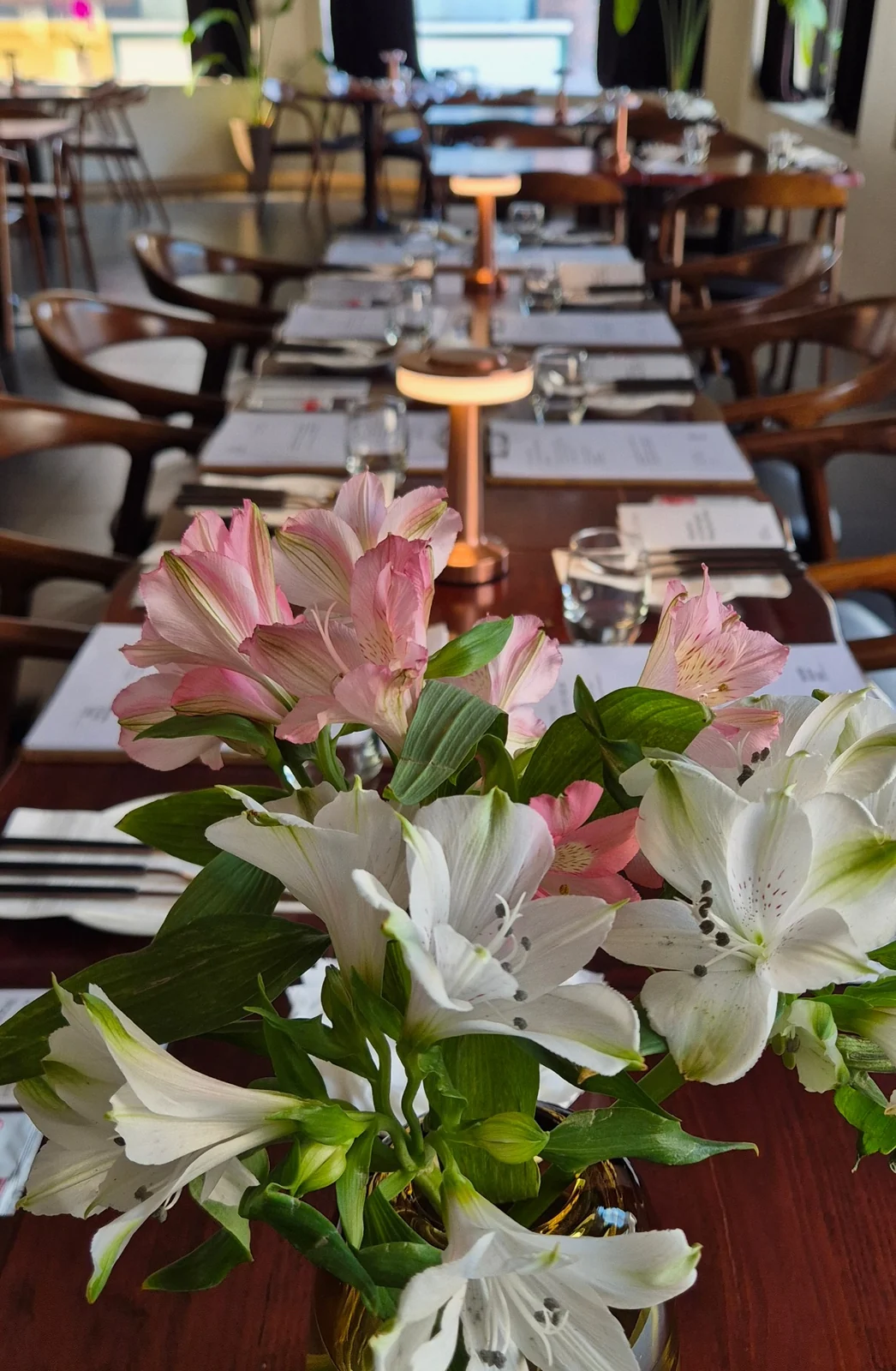Pink and white fresh flowers beside a long dining table