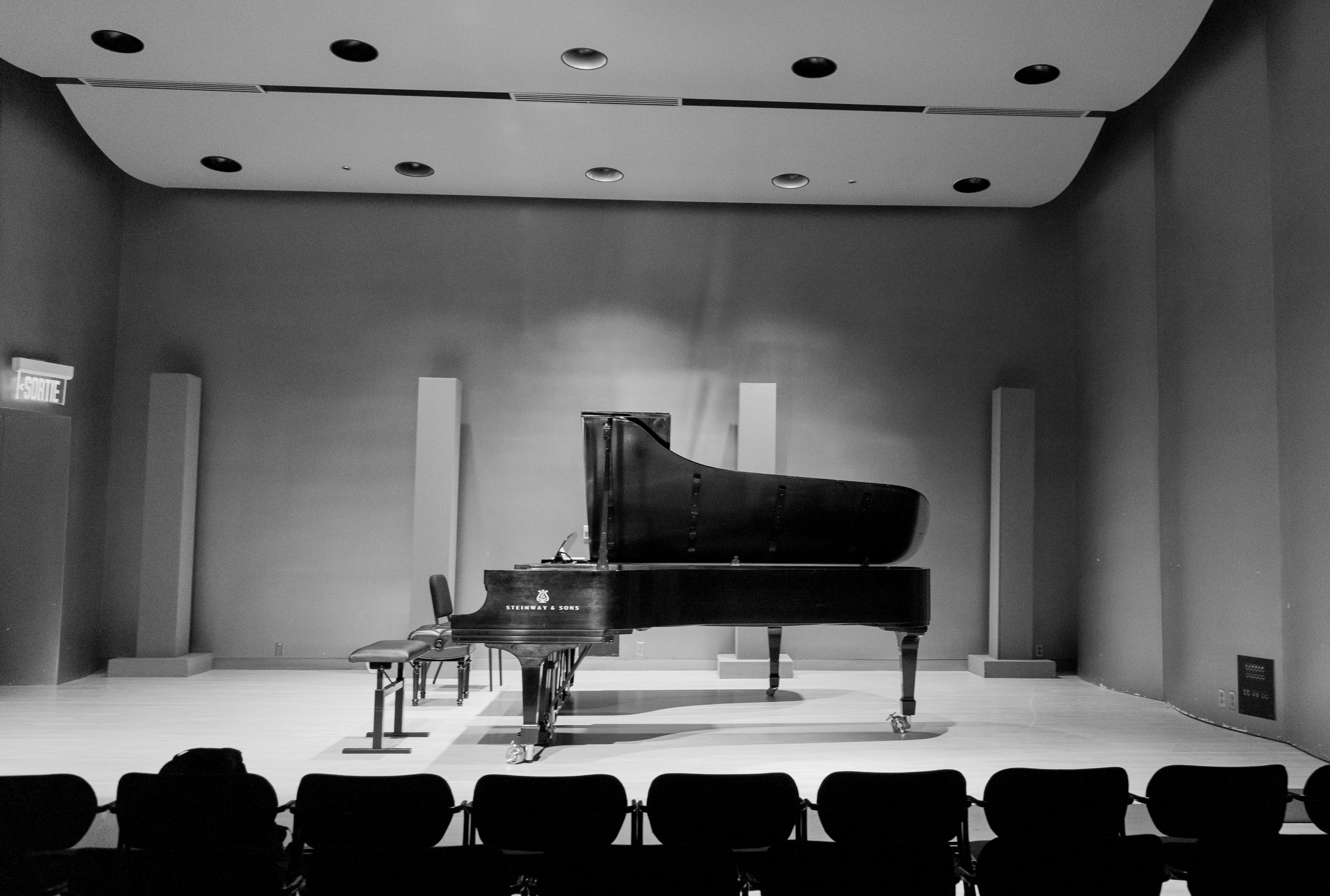 Black-and-white photograph of a grand piano in a concert hall