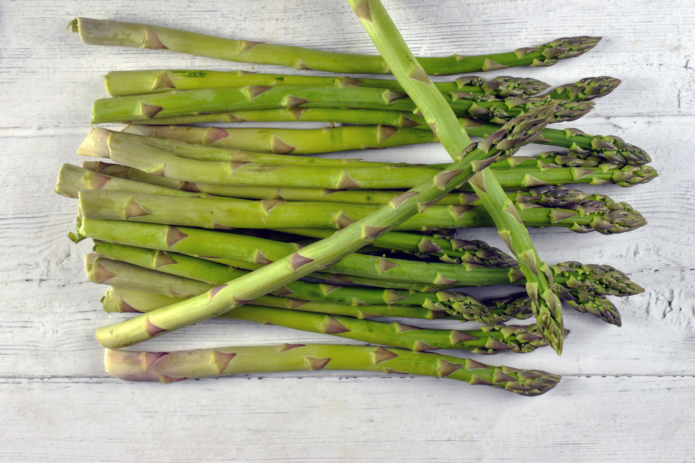 Fresh green asparagus on a white wooden board