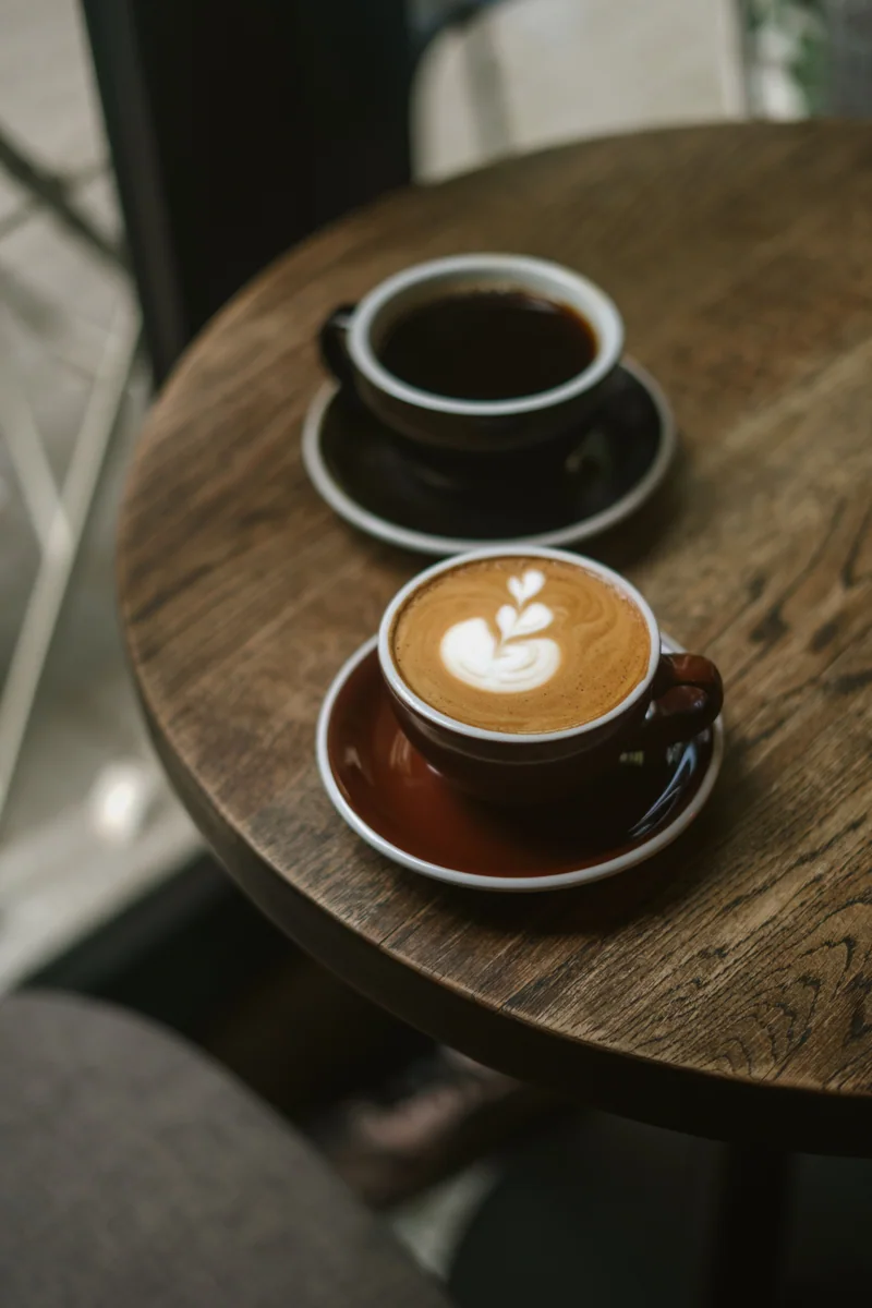 A small black coffee and a coffee drink with latte art on a table