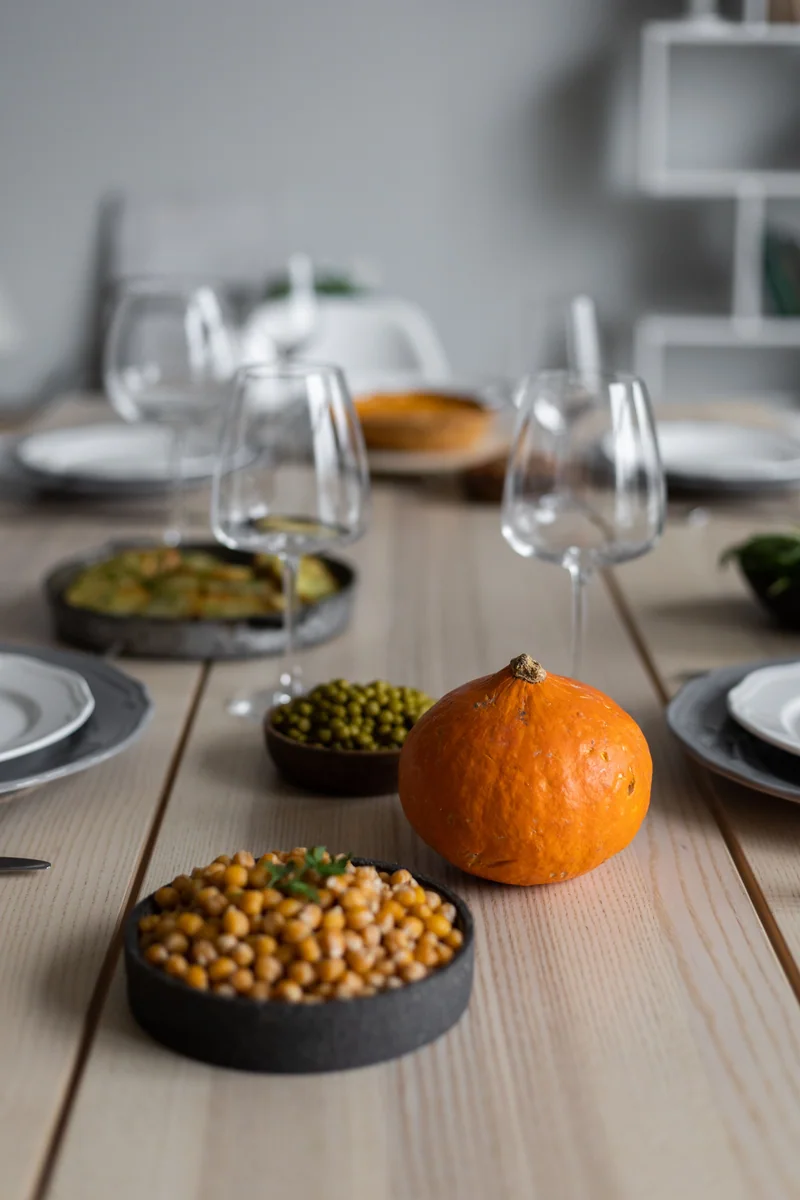A table with chickpea, squash and vegetable dishes and wine glasses