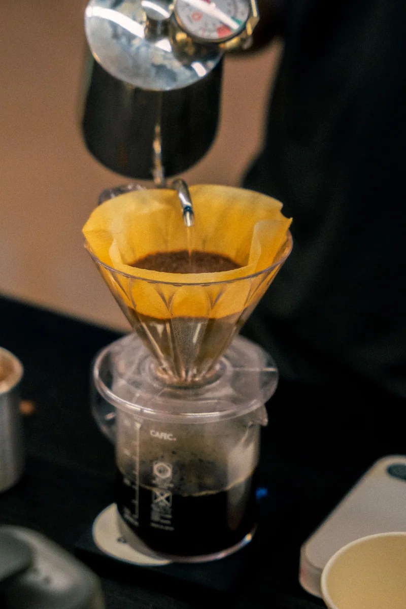 Water being poured from a gooseneck kettle onto coffee inside a paper filter