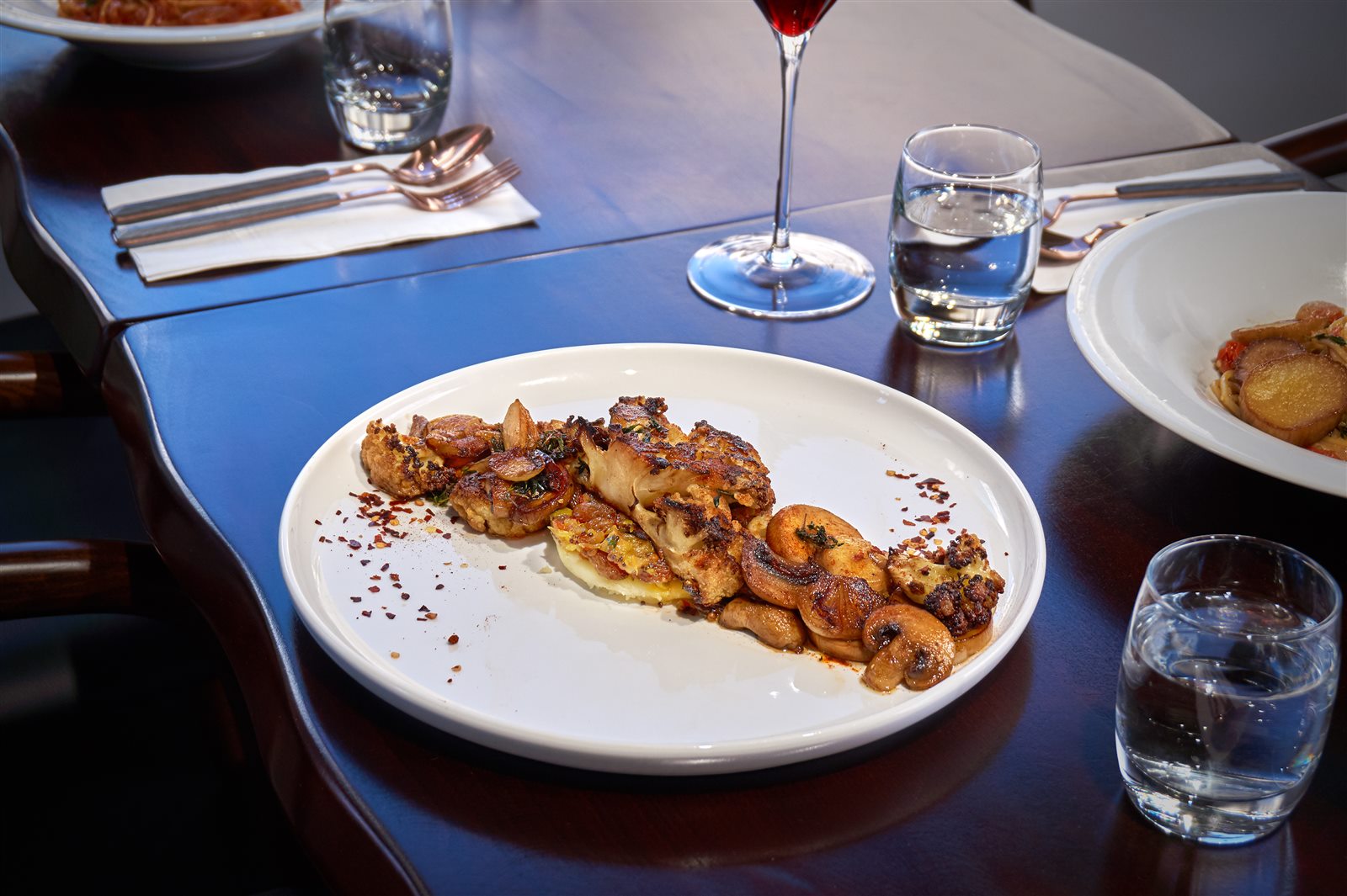 A plate of roasted cauliflower and mushrooms with orange and pickles